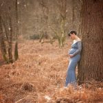 Woodland Maternity and Newborn Session pregant lady blue dress standing outdoors tree Samphire Photography