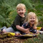 laughing siblings outdoors for woodland photoshoot