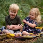 laughing siblings outdoors for woodland photoshoot