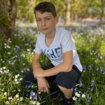 boy crouching among bluebells