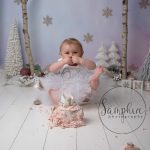 little girl with her foot in the air at her Christmas cake smash in Storrington