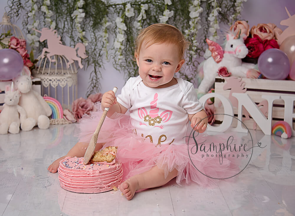 happy birthday girl enjoying her pretty unicorn theme cake smash Haywards Heath Sussex