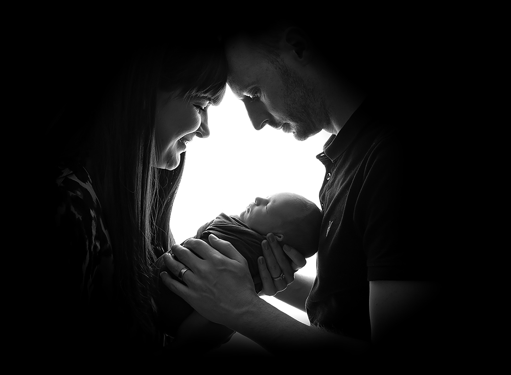 Backlit portrait of parents and their new baby boy by newborn portraits southwater and shoreham