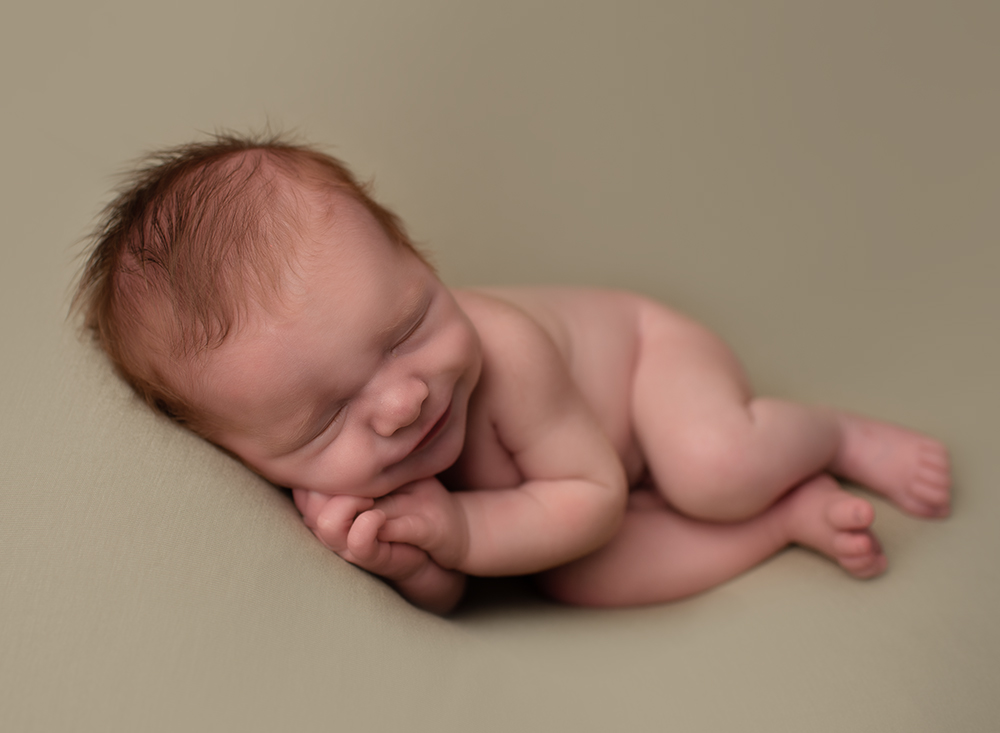 Smiling sleepy baby boy on his side by Samphire Photography 