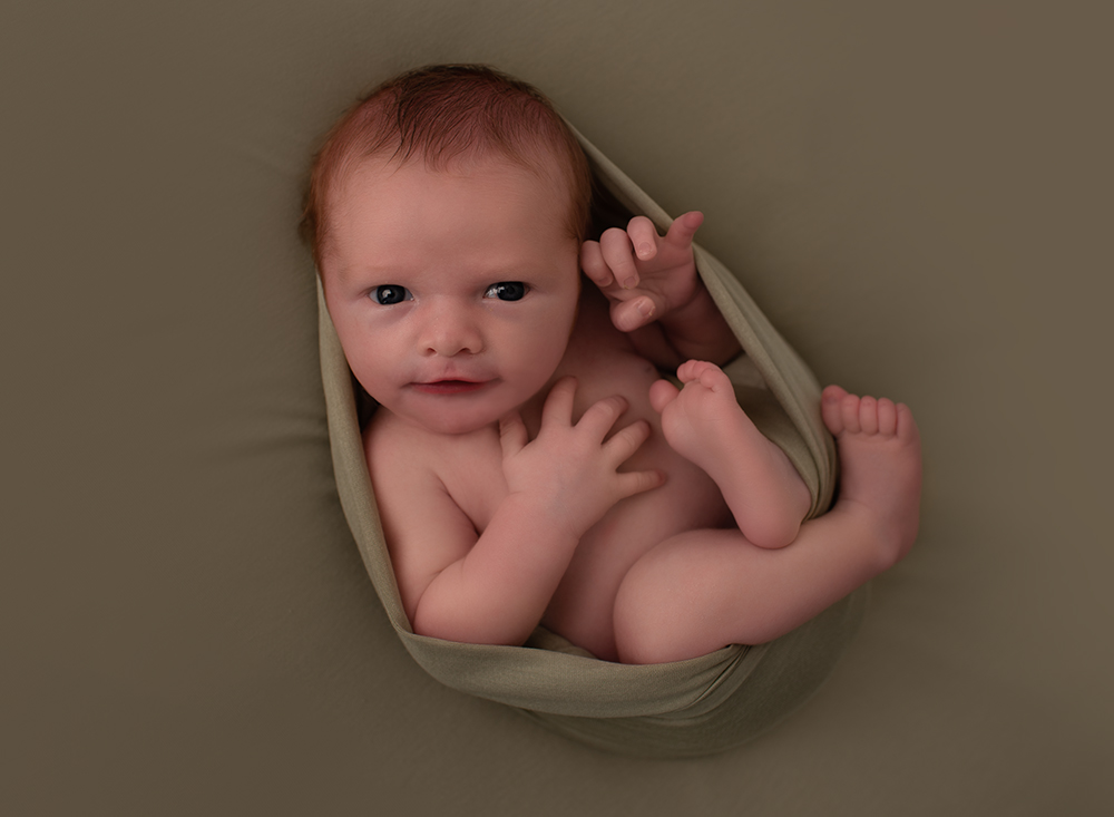 Awake newborn baby with cute litte finger raised by Newborn Photographer Southwater and Cuckfield