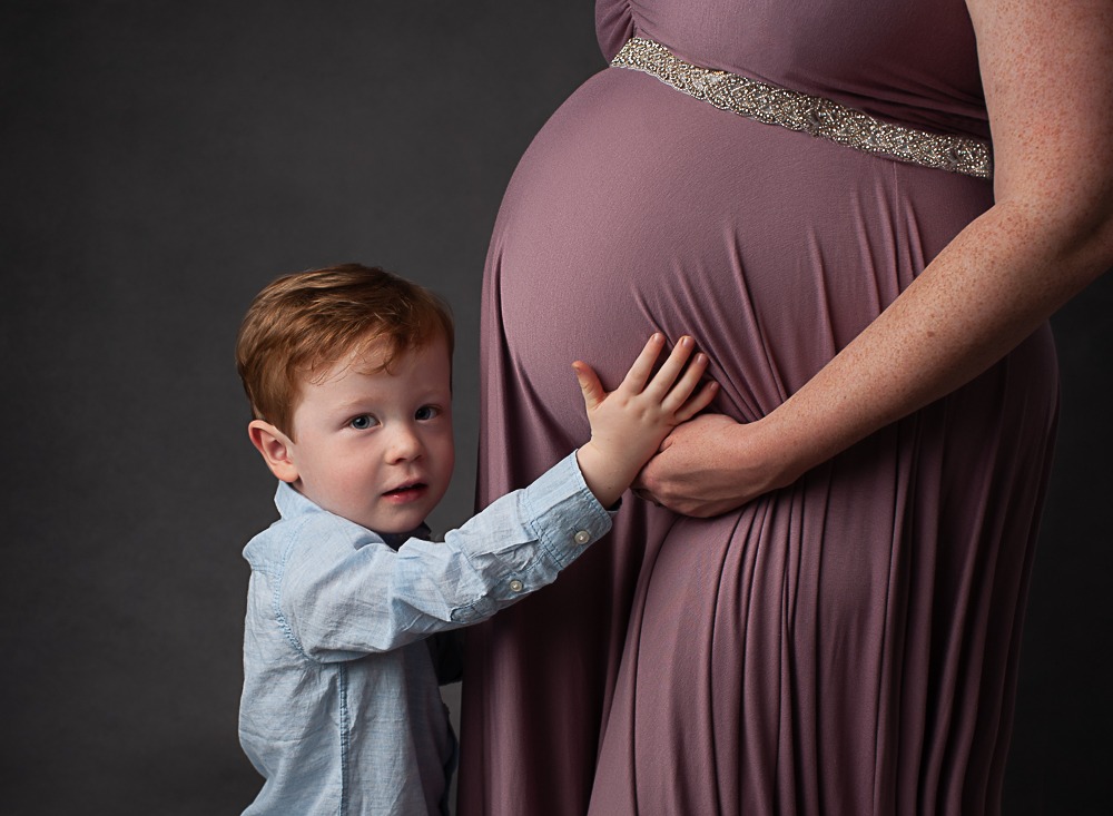 cute boy cuddling mummy's pregnant tummy