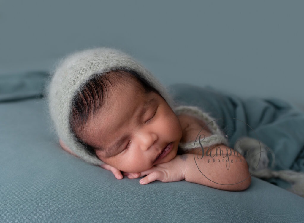 baby boy asleep wearing grey knitted hat by newborn photographer Dorking