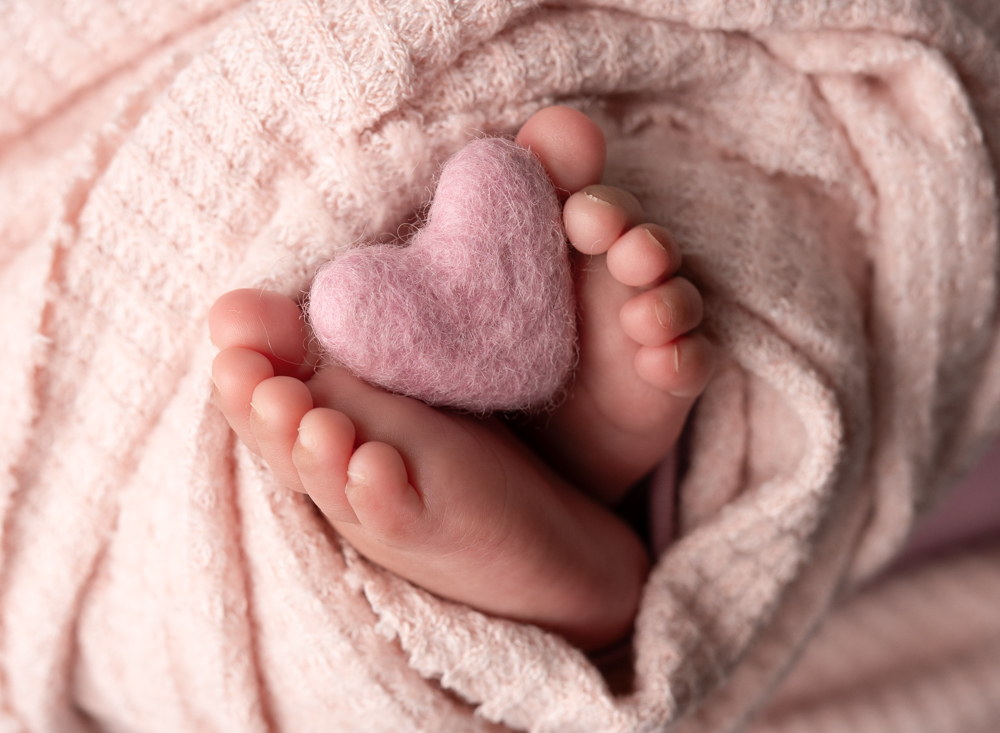 1 month newborn baby feet with felted pink heart