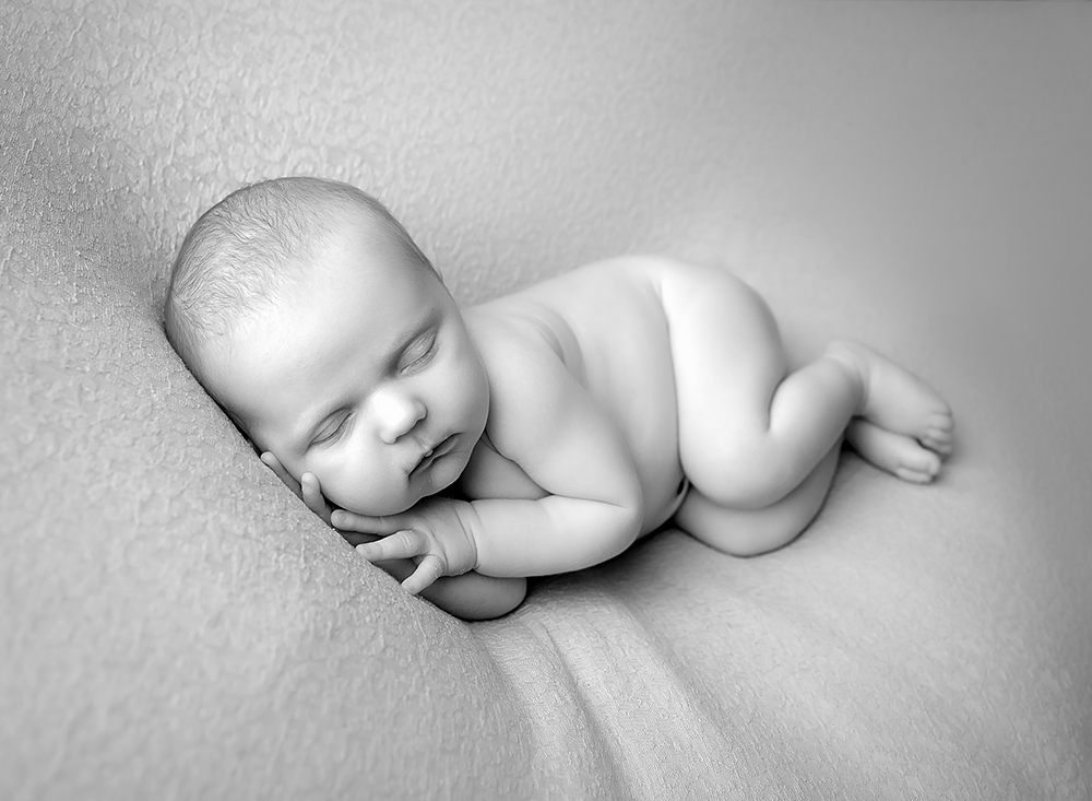 Black and white image of a sleepy baby by samphire photography showcasing baby portraits billinghurst