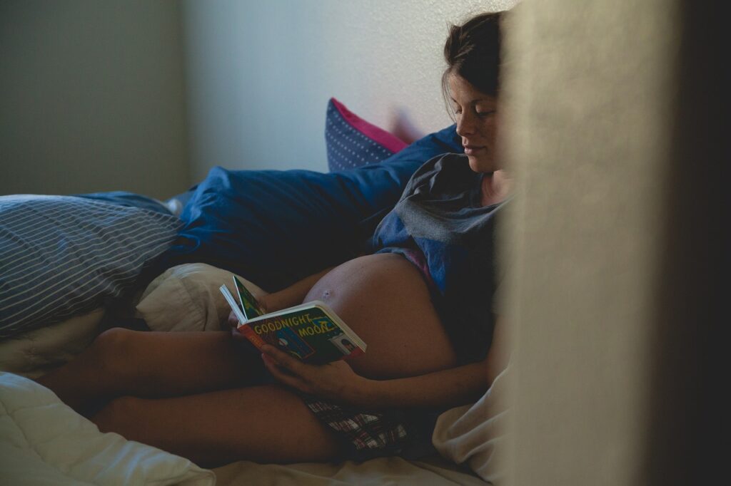 pregnant woman reading in bed
