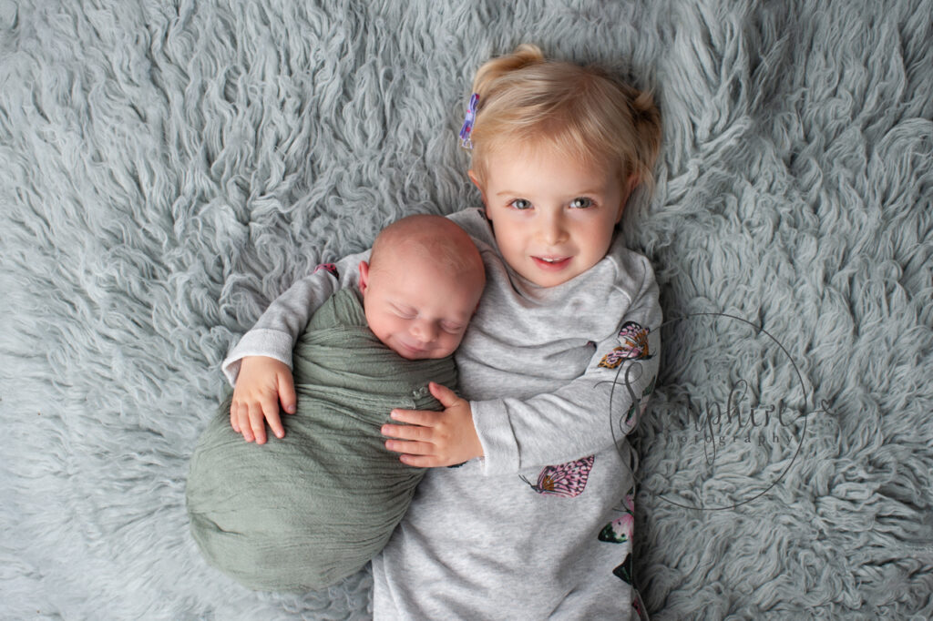 newborn asleep on flokati with sister