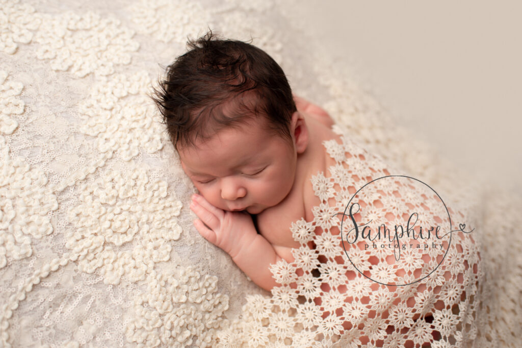 newborn asleep under pretty blanket