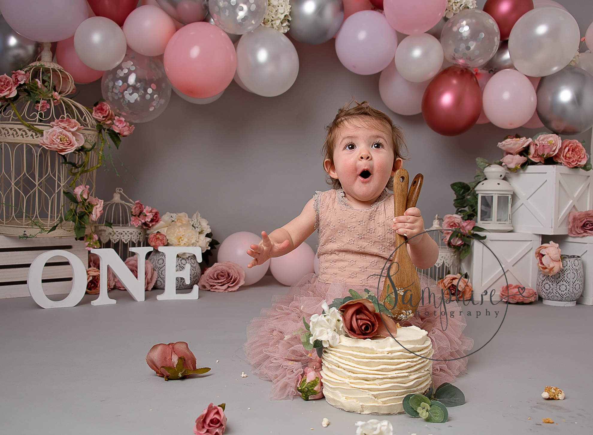 Excited girl enjoying her cake smash photoshoot Broadbridge Heath with pink and silver balloons