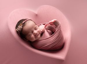 Smiling baby girl asleep in pink heart