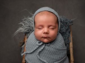 baby boy asleep wearing blue hat for studio portrait
